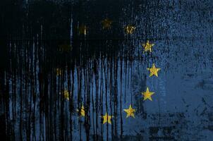 European union flag depicted in paint colors on old and dirty oil barrel wall closeup. Textured banner on rough background photo