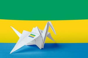 Gabon flag depicted on paper origami crane wing. Handmade arts concept photo