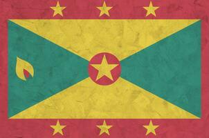 Grenada flag depicted in bright paint colors on old relief plastering wall. Textured banner on rough background photo