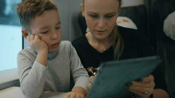 Mom and son playing on pad in train video