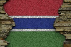 Gambia flag depicted in paint colors on old stone wall closeup. Textured banner on rock wall background photo