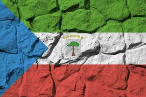 Equatorial Guinea flag depicted in paint colors on old stone wall closeup. Textured banner on rock wall background photo