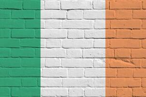 Ireland flag depicted in paint colors on old brick wall. Textured banner on big brick wall masonry background photo