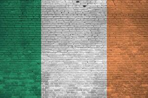 Ireland flag depicted in paint colors on old brick wall. Textured banner on big brick wall masonry background photo