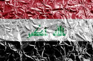 Iraq flag depicted in paint colors on shiny crumpled aluminium foil closeup. Textured banner on rough background photo