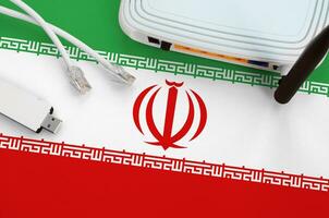 Iran flag depicted on table with internet rj45 cable, wireless usb wifi adapter and router. Internet connection concept photo