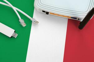 Italy flag depicted on table with internet rj45 cable, wireless usb wifi adapter and router. Internet connection concept photo