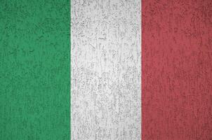 Italy flag depicted in bright paint colors on old relief plastering wall. Textured banner on rough background photo