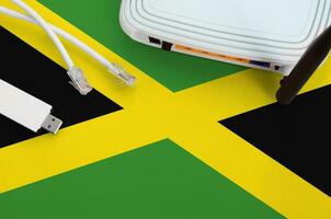 Jamaica flag depicted on table with internet rj45 cable, wireless usb wifi adapter and router. Internet connection concept photo