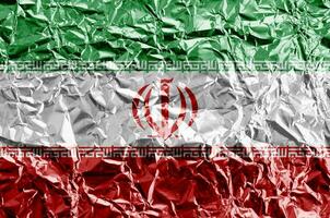 Iran flag depicted in paint colors on shiny crumpled aluminium foil closeup. Textured banner on rough background photo