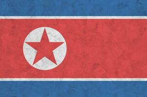 North Korea flag depicted in bright paint colors on old relief plastering wall. Textured banner on rough background photo