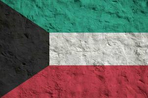 Kuwait flag depicted in bright paint colors on old relief plastering wall. Textured banner on rough background photo