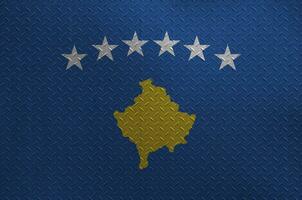 Kosovo flag depicted in paint colors on old brushed metal plate or wall closeup. Textured banner on rough background photo