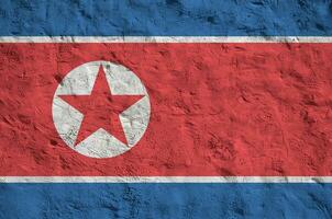 North Korea flag depicted in bright paint colors on old relief plastering wall. Textured banner on rough background photo