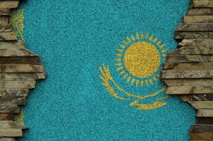 Kazakhstan flag depicted in paint colors on old stone wall closeup. Textured banner on rock wall background photo