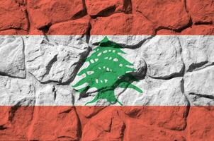 Lebanon flag depicted in paint colors on old stone wall closeup. Textured banner on rock wall background photo