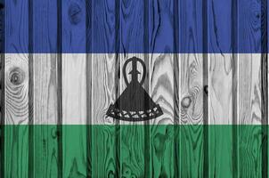 Lesotho flag depicted in bright paint colors on old wooden wall. Textured banner on rough background photo