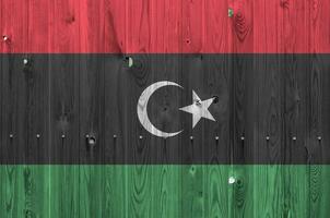 Libya flag depicted in bright paint colors on old wooden wall. Textured banner on rough background photo