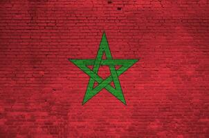 Morocco flag depicted in paint colors on old brick wall. Textured banner on big brick wall masonry background photo