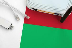 Madagascar flag depicted on table with internet rj45 cable, wireless usb wifi adapter and router. Internet connection concept photo