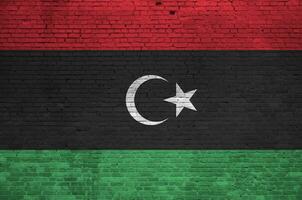 Libya flag depicted in paint colors on old brick wall. Textured banner on big brick wall masonry background photo
