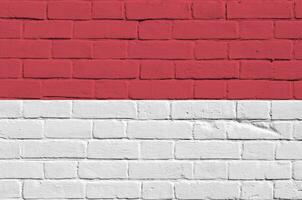 Monaco flag depicted in paint colors on old brick wall. Textured banner on big brick wall masonry background photo