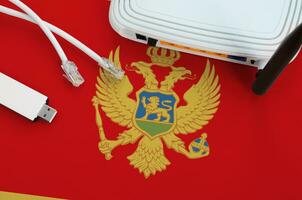 Montenegro flag depicted on table with internet rj45 cable, wireless usb wifi adapter and router. Internet connection concept photo