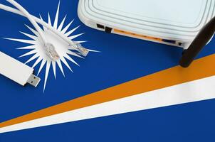 Marshall Islands flag depicted on table with internet rj45 cable, wireless usb wifi adapter and router. Internet connection concept photo