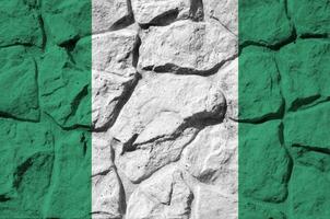 Nigeria flag depicted in paint colors on old stone wall closeup. Textured banner on rock wall background photo