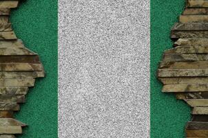 Nigeria flag depicted in paint colors on old stone wall closeup. Textured banner on rock wall background photo