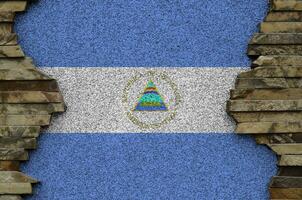 Nicaragua flag depicted in paint colors on old stone wall closeup. Textured banner on rock wall background photo