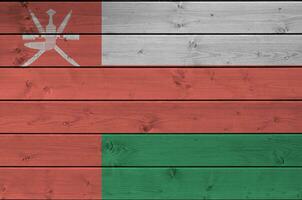 Oman flag depicted in bright paint colors on old wooden wall. Textured banner on rough background photo