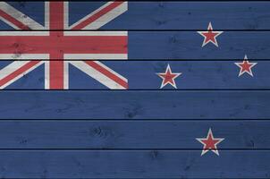 New Zealand flag depicted in bright paint colors on old wooden wall. Textured banner on rough background photo