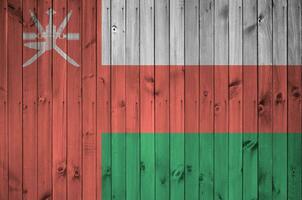 Oman flag depicted in bright paint colors on old wooden wall. Textured banner on rough background photo