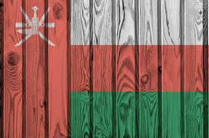 Oman flag depicted in bright paint colors on old wooden wall. Textured banner on rough background photo