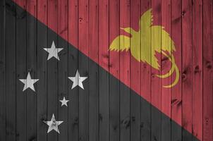 Papua New Guinea flag depicted in bright paint colors on old wooden wall. Textured banner on rough background photo