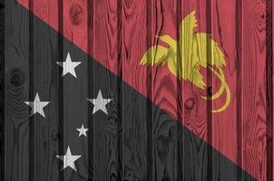 Papua New Guinea flag depicted in bright paint colors on old wooden wall. Textured banner on rough background photo