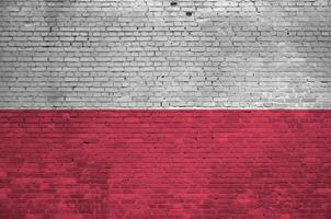 Poland flag depicted in paint colors on old brick wall. Textured banner on big brick wall masonry background photo