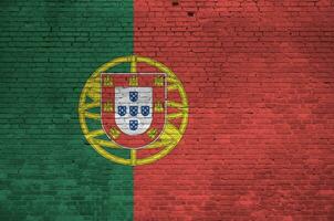 Portugal flag depicted in paint colors on old brick wall. Textured banner on big brick wall masonry background photo