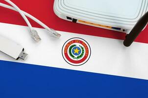 Paraguay flag depicted on table with internet rj45 cable, wireless usb wifi adapter and router. Internet connection concept photo