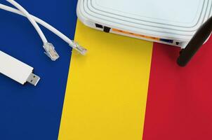 Romania flag depicted on table with internet rj45 cable, wireless usb wifi adapter and router. Internet connection concept photo