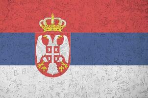 Serbia flag depicted in bright paint colors on old relief plastering wall. Textured banner on rough background photo