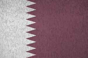 Qatar flag depicted in bright paint colors on old relief plastering wall. Textured banner on rough background photo