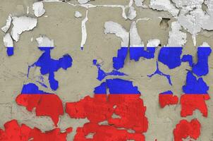 Russia flag depicted in paint colors on old obsolete messy concrete wall closeup. Textured banner on rough background photo