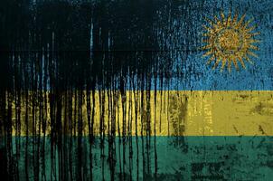 Rwanda flag depicted in paint colors on old and dirty oil barrel wall closeup. Textured banner on rough background photo
