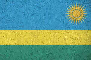 Rwanda flag depicted in bright paint colors on old relief plastering wall. Textured banner on rough background photo