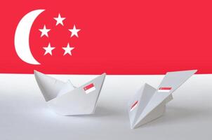 Singapore flag depicted on paper origami airplane and boat. Handmade arts concept photo