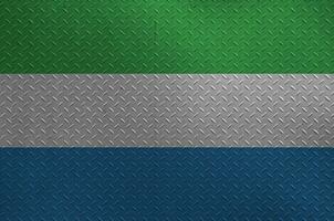 Sierra Leone flag depicted in paint colors on old brushed metal plate or wall closeup. Textured banner on rough background photo