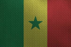 Senegal flag depicted in paint colors on old brushed metal plate or wall closeup. Textured banner on rough background photo