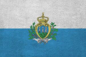 San Marino flag depicted in bright paint colors on old relief plastering wall. Textured banner on rough background photo
